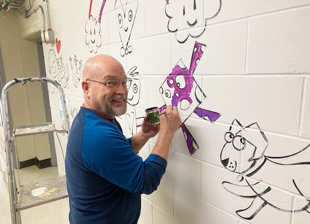 IMG_5591 Staff members at Harrington Elementary School add their personal touches to the hallway mural.