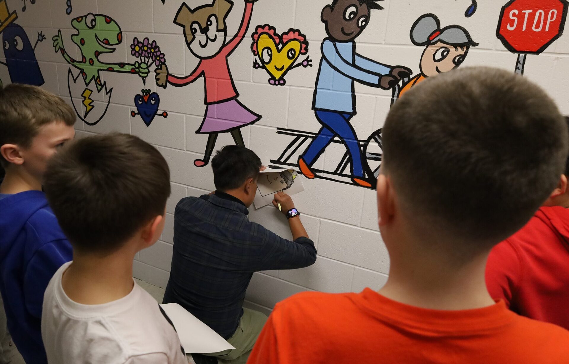 IMG_9411 Artist Bren Bataclan signs drawings created by Harrington Elementary School students during the unveiling of his hallway mural on Friday, March 20, 2026.