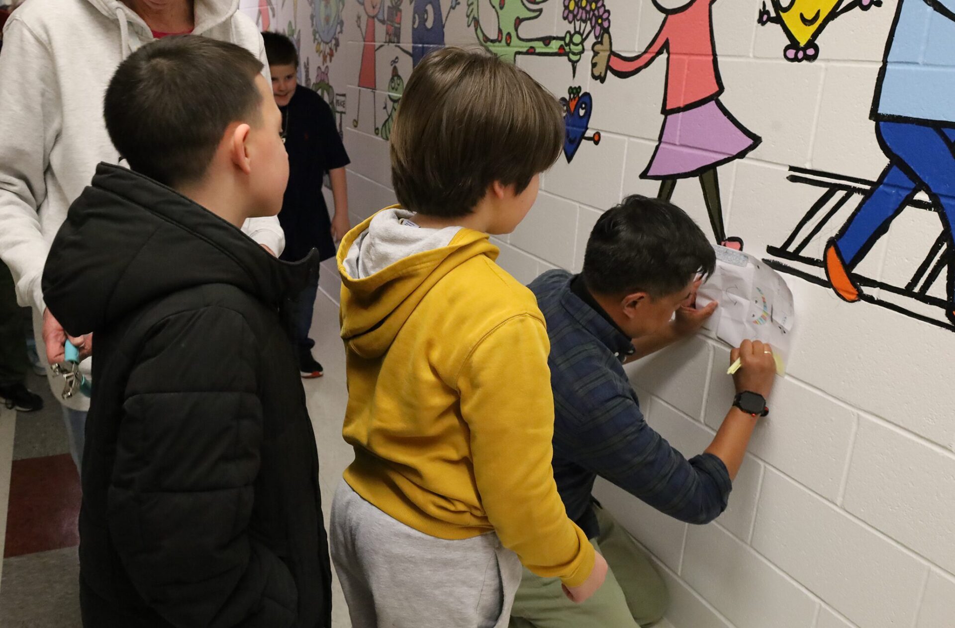 IMG_9413 Artist Bren Bataclan signs drawings created by Harrington Elementary School students during the unveiling of his hallway mural on Friday, March 20, 2026.