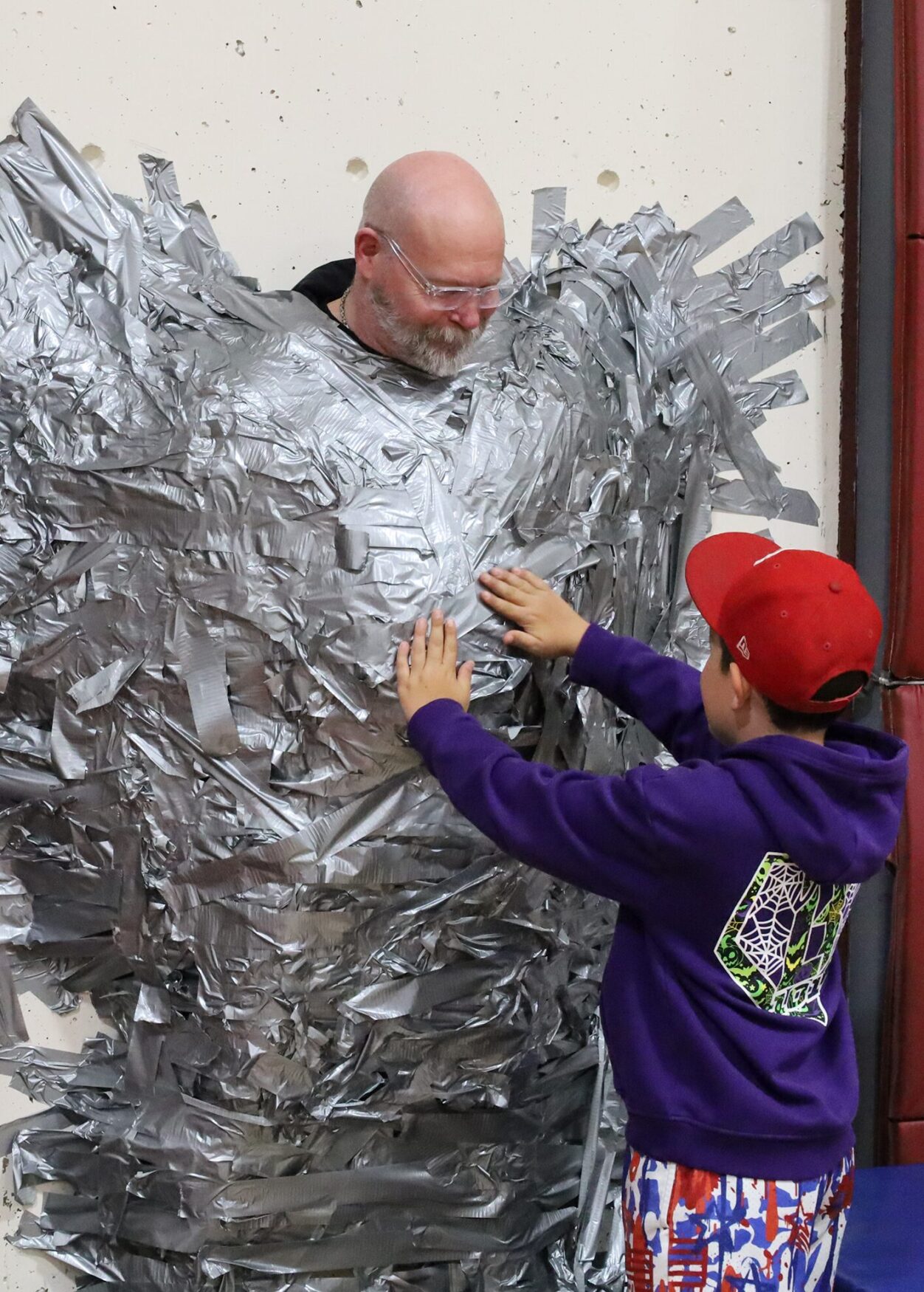 Harrington Elementary School students duct tape Principal Rob Asselin to the gymnasium wall on Thursday, April 30, as a fundraiser for the fourth grade class.