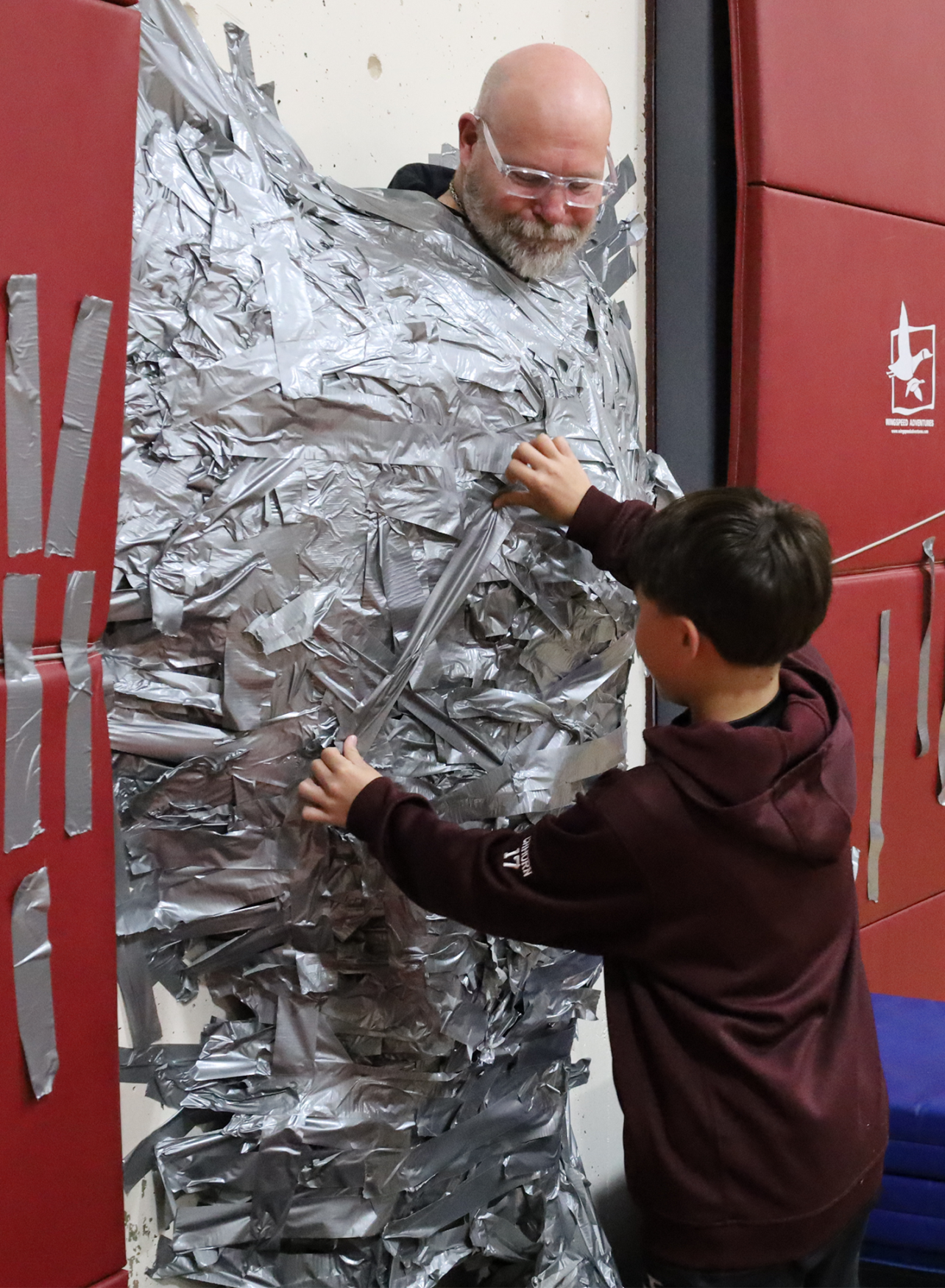 Harrington Elementary School students duct tape Principal Rob Asselin to the gymnasium wall on Thursday, April 30, as a fundraiser for the fourth grade class.