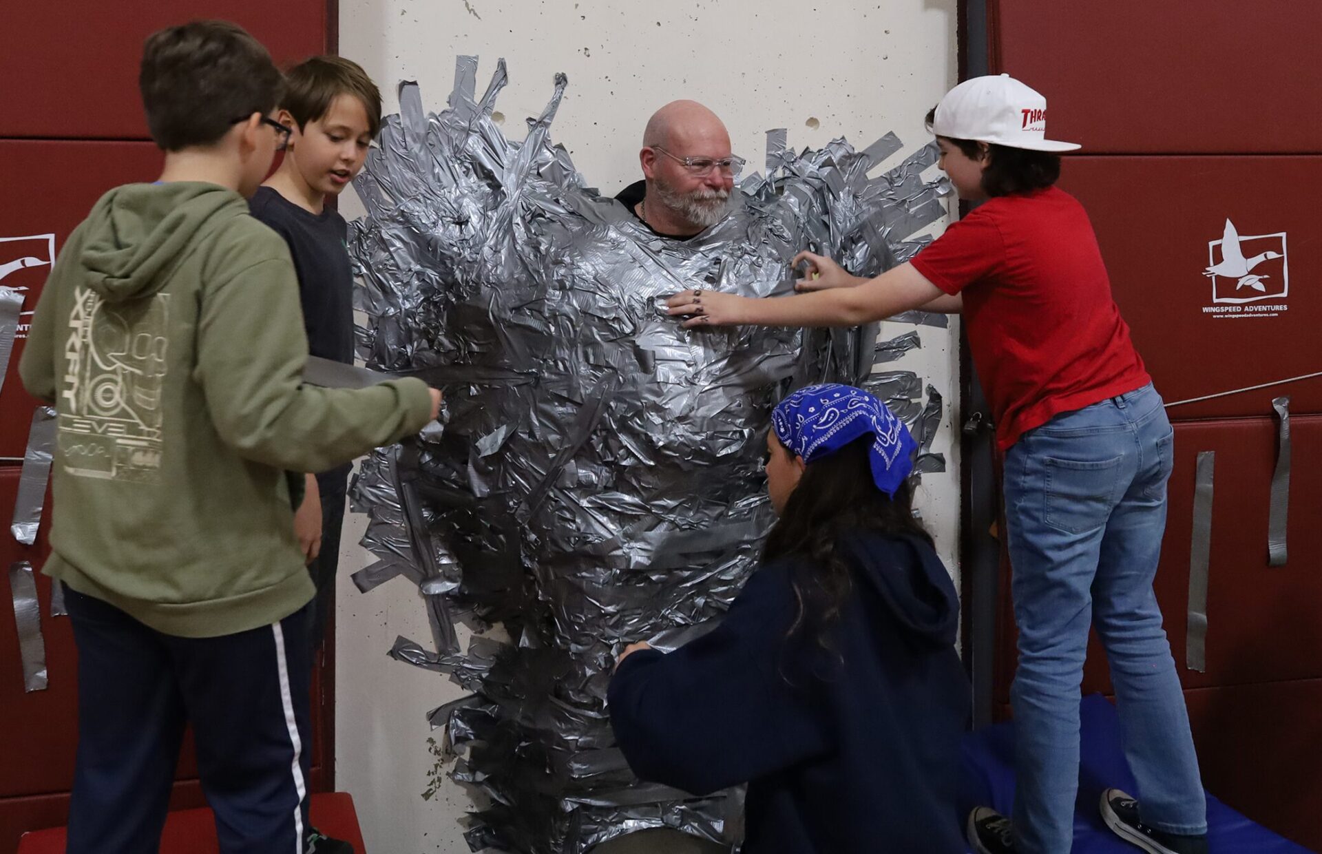 Harrington Elementary School students duct tape Principal Rob Asselin to the gymnasium wall on Thursday, April 30, as a fundraiser for the fourth grade class.