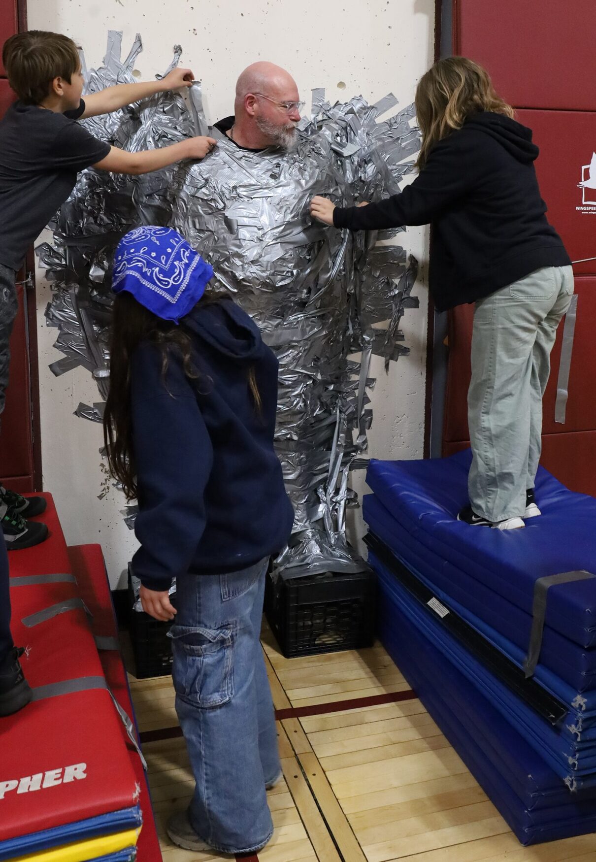 Harrington Elementary School students duct tape Principal Rob Asselin to the gymnasium wall on Thursday, April 30, as a fundraiser for the fourth grade class.