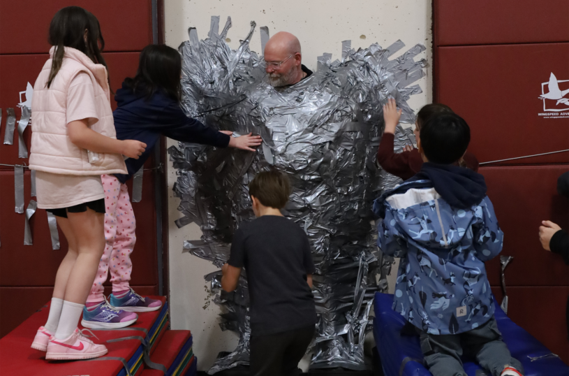Harrington Elementary School students duct tape Principal Rob Asselin to the gymnasium wall on Thursday, April 30, as a fundraiser for the fourth grade class.