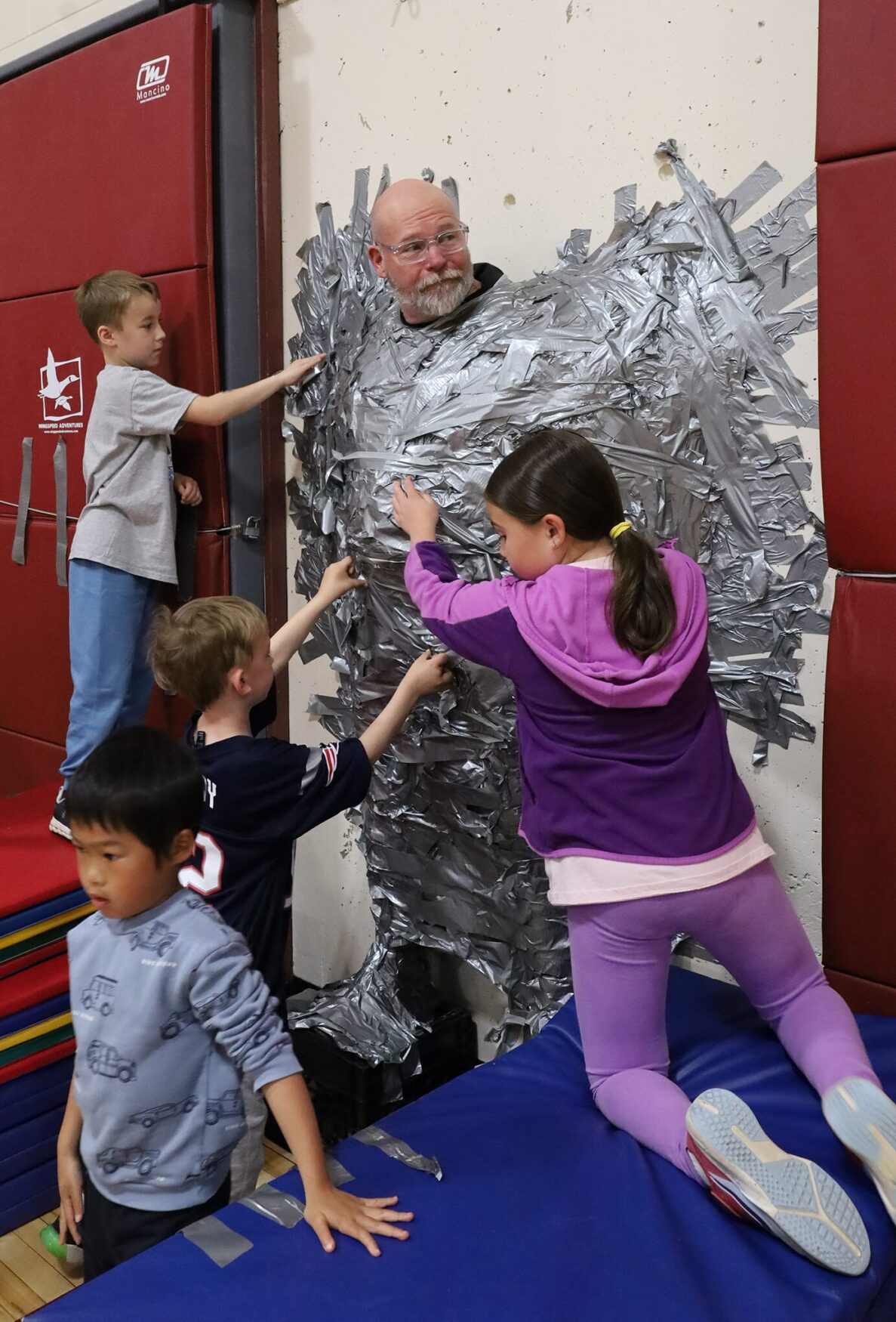 Harrington Elementary School students duct tape Principal Rob Asselin to the gymnasium wall on Thursday, April 30, as a fundraiser for the fourth grade class.