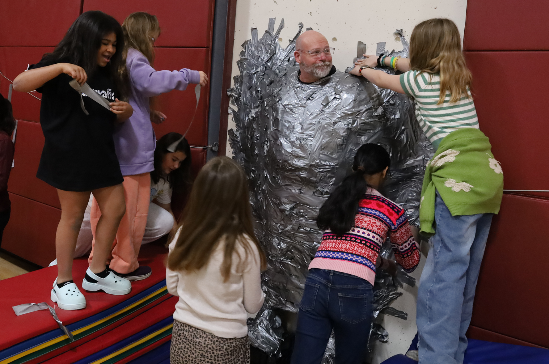 Harrington Elementary School students duct tape Principal Rob Asselin to the gymnasium wall on Thursday, April 30, as a fundraiser for the fourth grade class.