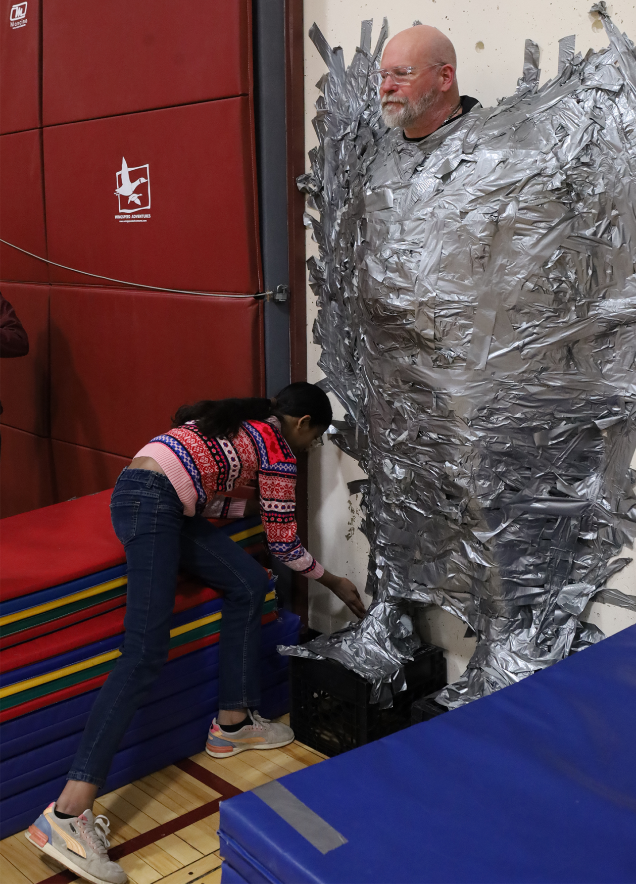 Harrington Elementary School students duct tape Principal Rob Asselin to the gymnasium wall on Thursday, April 30, as a fundraiser for the fourth grade class.