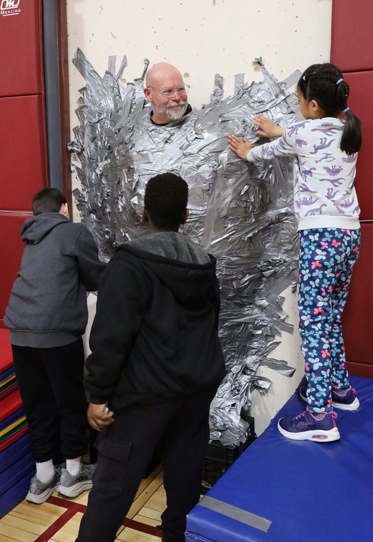 Harrington Elementary School students duct tape Principal Rob Asselin to the gymnasium wall on Thursday, April 30, as a fundraiser for the fourth grade class.