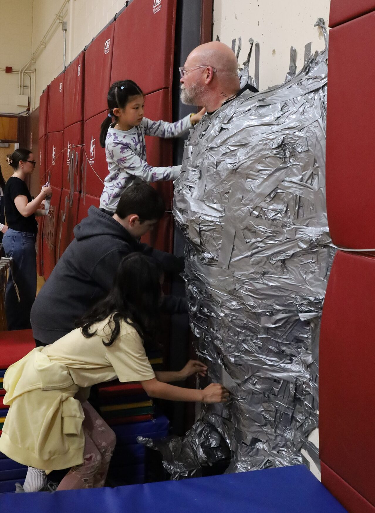 Harrington Elementary School students duct tape Principal Rob Asselin to the gymnasium wall on Thursday, April 30, as a fundraiser for the fourth grade class.