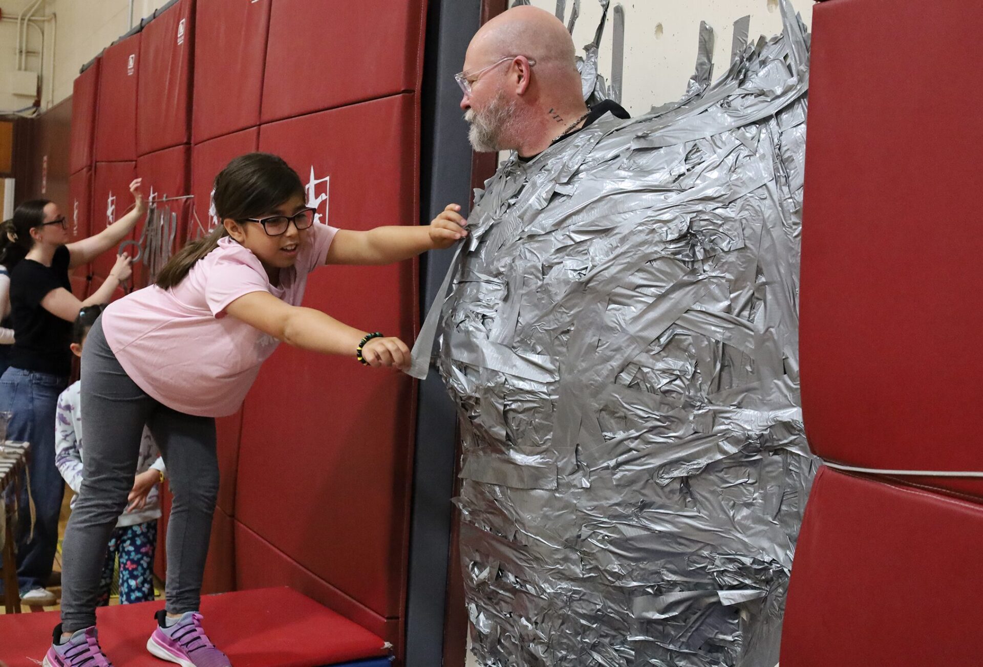 Harrington Elementary School students duct tape Principal Rob Asselin to the gymnasium wall on Thursday, April 30, as a fundraiser for the fourth grade class.
