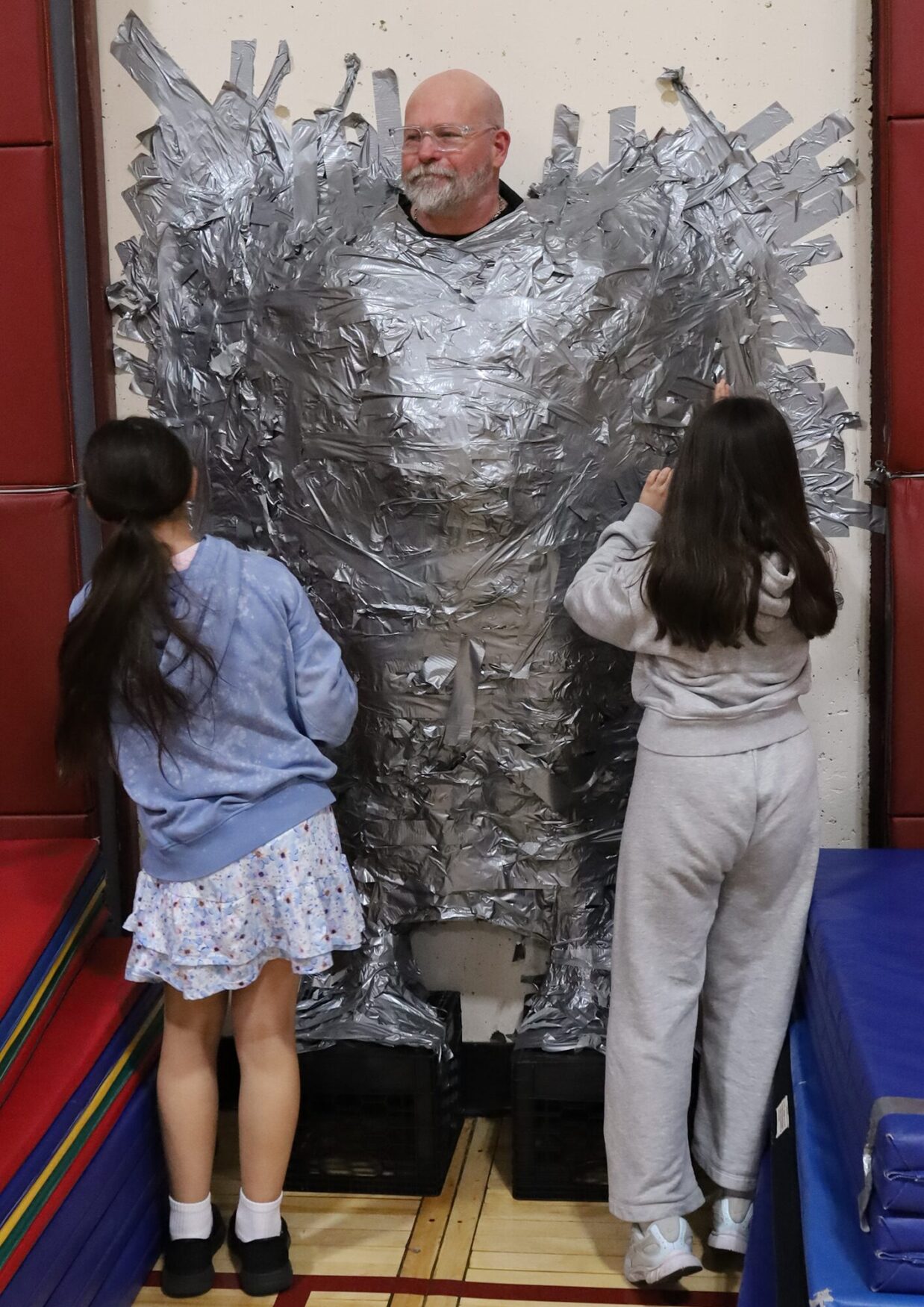 Harrington Elementary School students duct tape Principal Rob Asselin to the gymnasium wall on Thursday, April 30, as a fundraiser for the fourth grade class.