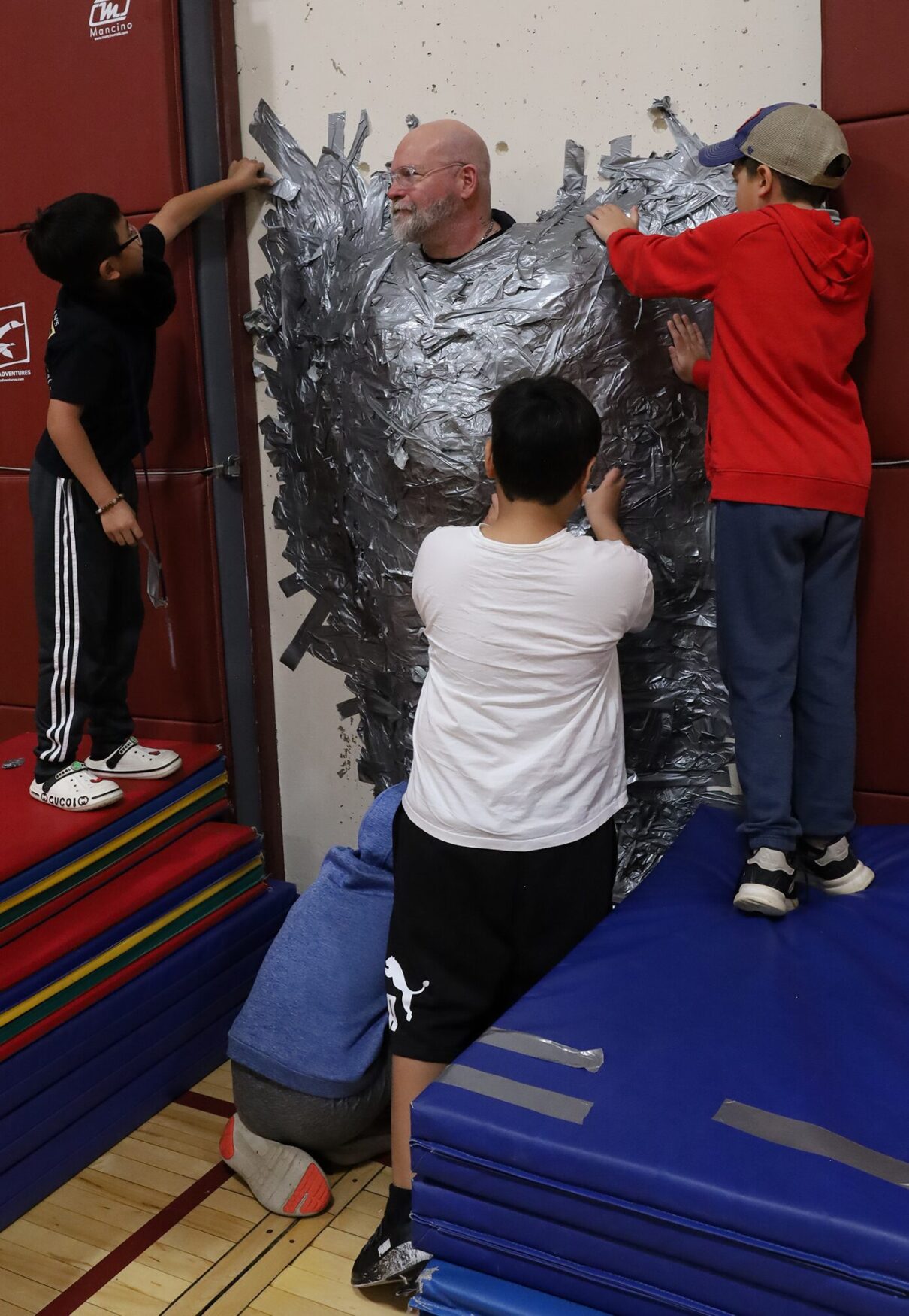 Harrington Elementary School students duct tape Principal Rob Asselin to the gymnasium wall on Thursday, April 30, as a fundraiser for the fourth grade class.