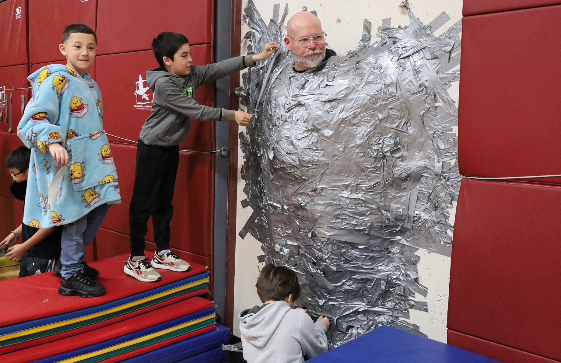 Harrington Elementary School students duct tape Principal Rob Asselin to the gymnasium wall on Thursday, April 30, as a fundraiser for the fourth grade class.