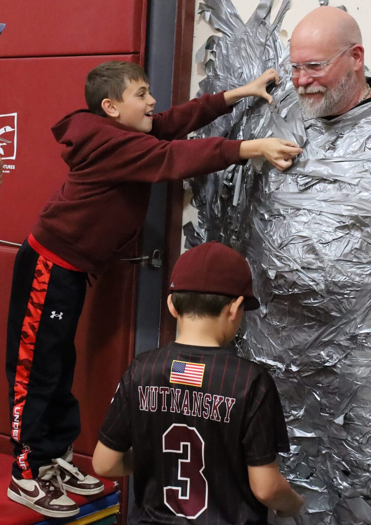 Harrington Elementary School students duct tape Principal Rob Asselin to the gymnasium wall on Thursday, April 30, as a fundraiser for the fourth grade class.