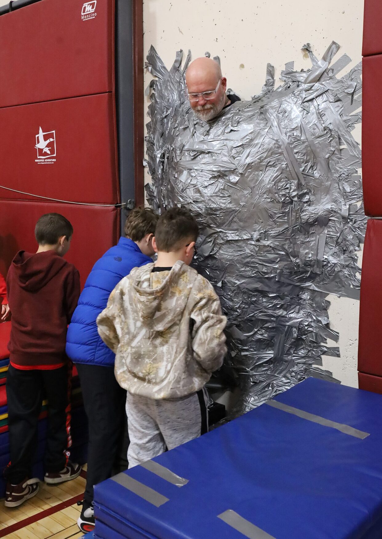 Harrington Elementary School students duct tape Principal Rob Asselin to the gymnasium wall on Thursday, April 30, as a fundraiser for the fourth grade class.